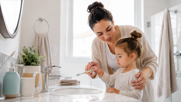 Mother helping young child with a healthy tooth brushing routine